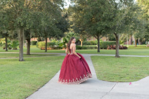 A sweet 16 orlando photo shoot with Khim Higgins photography of a girl wearing a red dress at UCF campus.