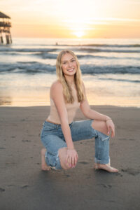 A high school senior girl is sitting on a beach being photographed by Orlando Senior Photographer, Khim Higgins.