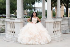 A girl wearing a blush pink quinceaner dress is posing for Khim Higgins Photography at Cranes Roost park.