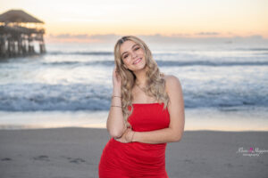 senior girl in a red dress at the beach for her orlando senior portrait session