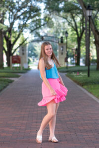 Lake Mary senior girl in a blue tank top and pink skirt is twirling while holding her skirt.