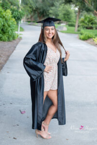 Oviedo Senior Girl is wearing her black cap and gown posing for Orlando Senior Photographer, Khim Higgins at the UCF campus.