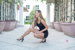 Oviedo senior girl wearing a black mini dress is half sitting down and posing for Orlando Senior Photographer, Khim Higgins.