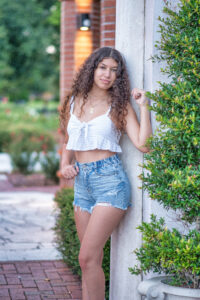 A lake mary senior girl leaning against a white pillar.