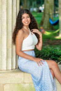 A lake mary senior girl sitting on a cement pillar.