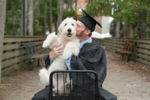 UCF grad holding his dog sitting on a chair at Student Union.