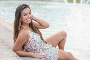 A senior from Oviedo High School is sitting on the steps of UCF Reflection Pond.