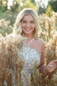 Senior girl is wearing a formal short dress in a field of tall grass