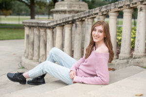 A lake mary high school senior girl is sitting on some stairs and leaning back with her left elbow.