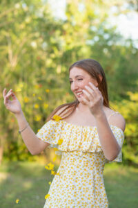 OHS senior girl in a yellow dress is tossing up some flower confetti as Khim Higgins Photography captures her picture.