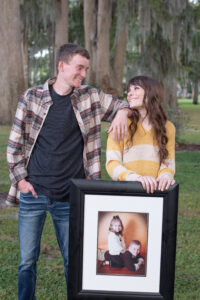 Timber Creek senior girl and her brother smiling at each other as she holds a baby picture of the two of them as Orlando Senior Photographer works with them.