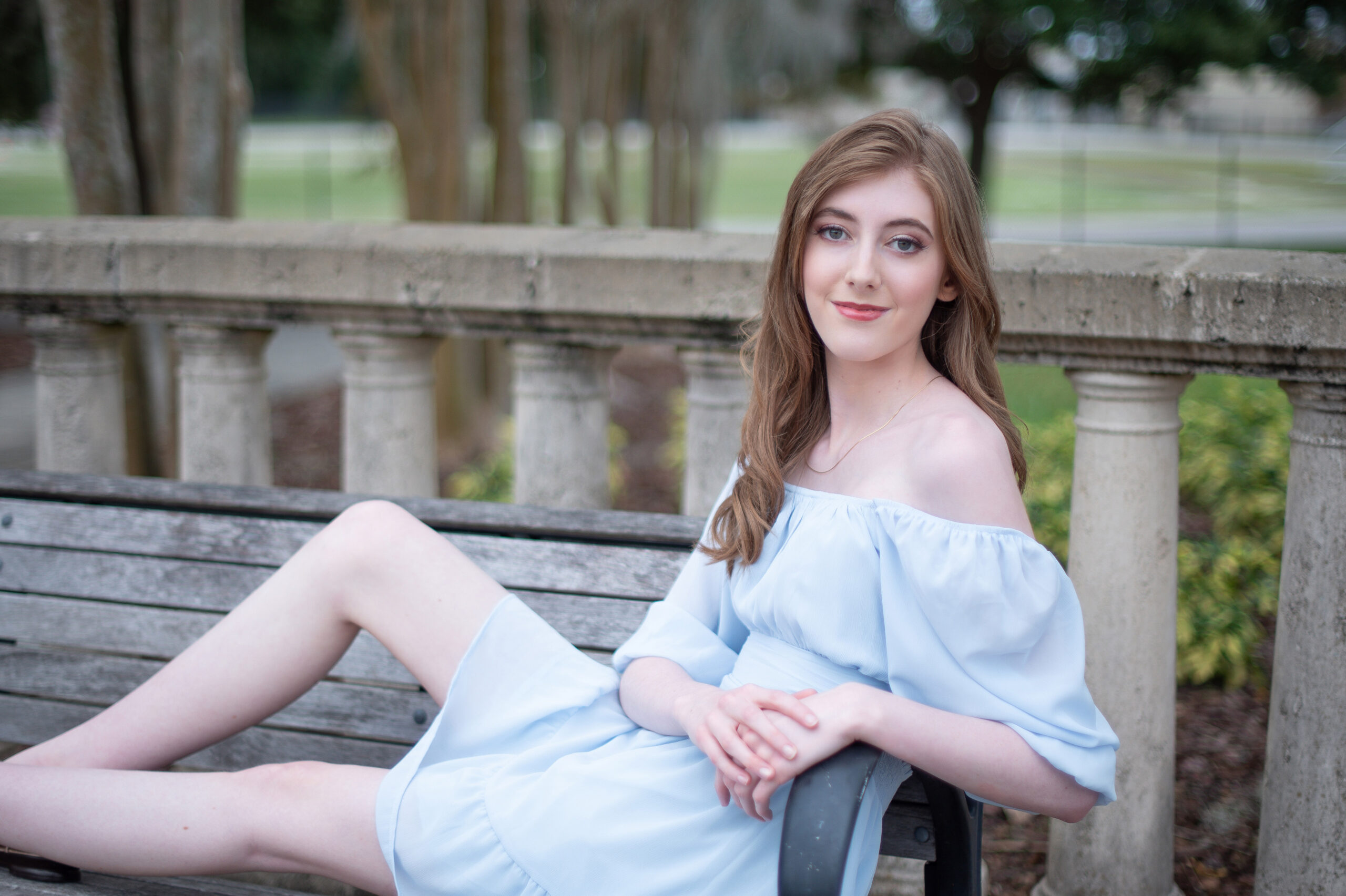 A high school senior girl sitting on a bench.