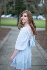 A lake mary high school senior girl is wearing a blue dress and turns around looking over her left shoulder.