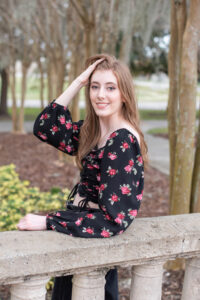 A lake mary high school senior girl is leaning on a cement railing.