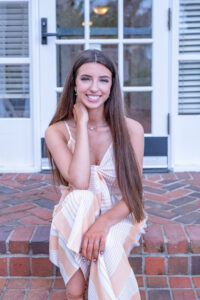 Oviedo senior girl is sitting on stairs while Orlando Senior Photographer, Khim Higgins takes her picture.