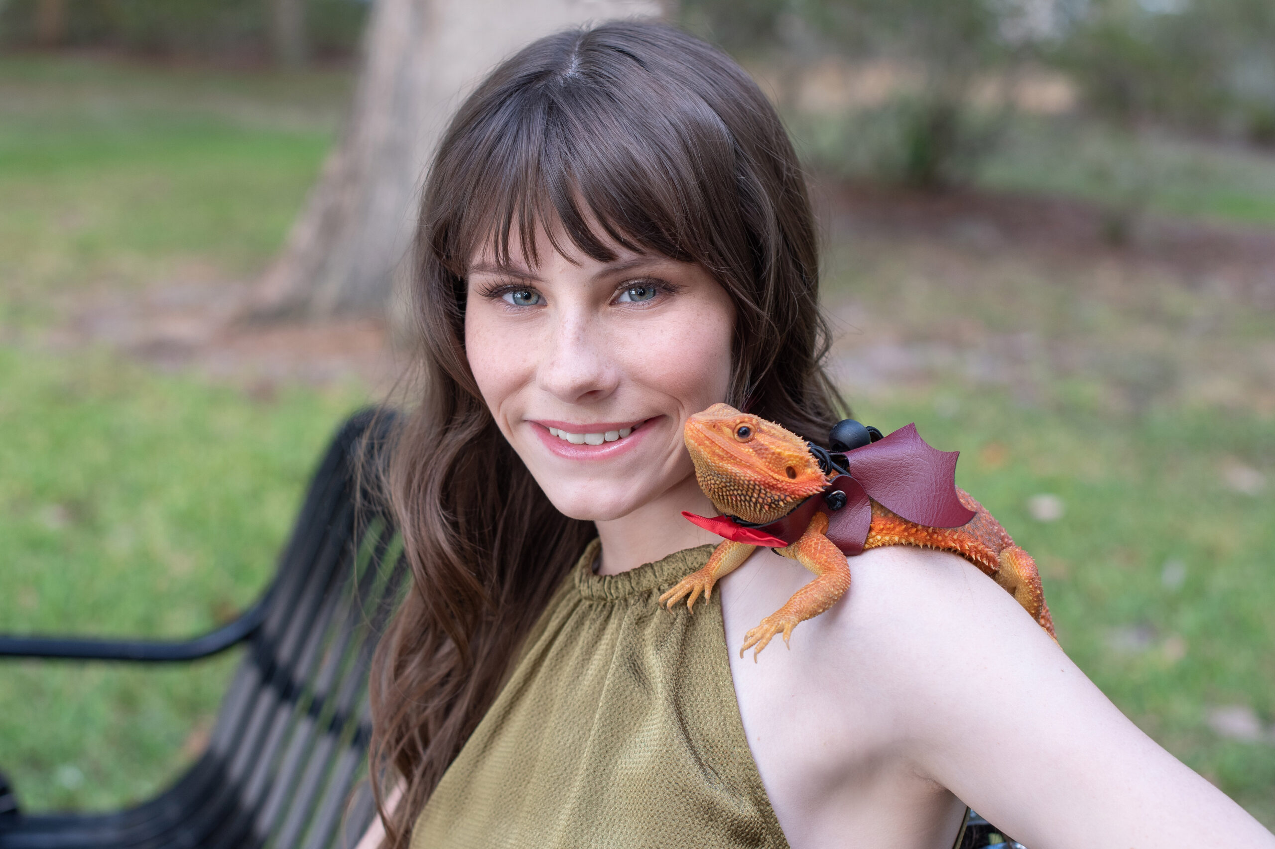 Timber Creek High School senior girl sitting on a bench with her pet bearded dragon sitting on her shoulder as Khim Higgins Photography photographs her.