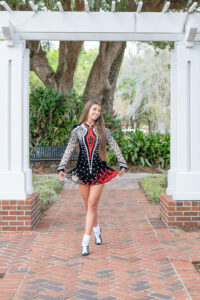 A senior girl is wearing her black and red dance outfit with Khim Higgins photographer doing her senior photos.