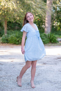 senior girl in a blue dress is twirling in her dress.