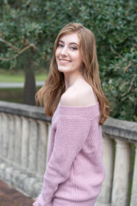 A lake mary senior high school girl is wearing a pink off the shoulder sweater and looking over her left shoulder.