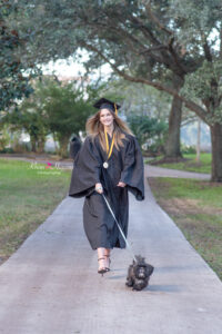 ucf graduate is wearing her cap and gown and walking her dog