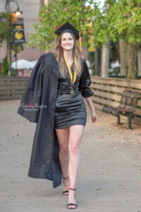 ucf graduate is holding her graduation gown and walking.