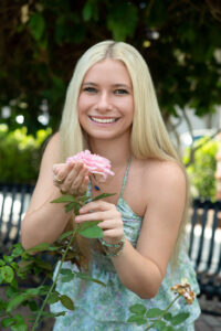 A Hagerty senior girl in a blue dress is holding a pink rose.