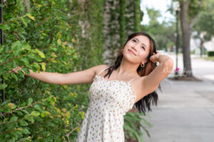 Orlando senior girl in a white sundress is holding a rail and leaning back looking up at the sky.