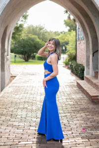 senior girl in a blue formal dress is standing at Casa Feliz archway.