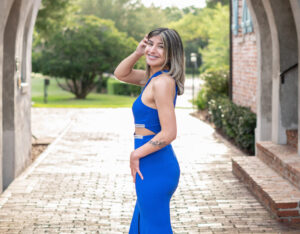 senior girl in a blue formal dress is standing at Casa Feliz archway.