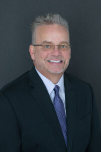 a white male in a black suit is sitting down for his professional headshot in Oviedo, Florida.