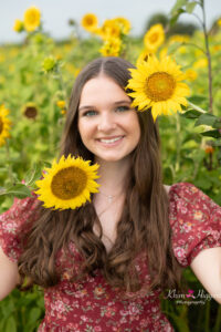 orlando senior girl is holding sunflowers near her face while orlando senior photographer khim higgins takes her photos