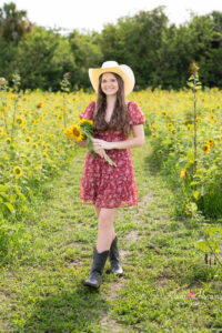 orlando senior girl in a red dress is standing in a sunflower field with khim higgins photography.