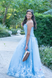 a sweet 16 girl in a blue dress is holding her shoes and smiling at Khim Higgins Photography.