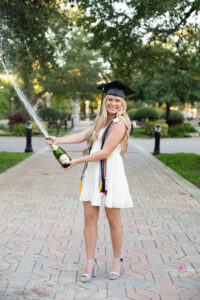 oviedo girl in white dress pops champagne at senior photo shoot.