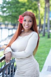 Senior girl in light gray dress sitting by the lake