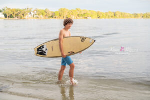 Orlando senior photographer captures teen boy posing with surfboard during senior photo session.