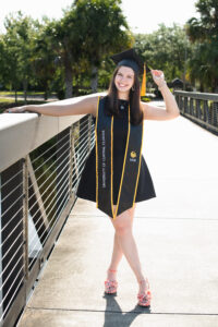 UCF grad standing on a bridge