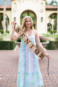 Senior girl holding a senior banner being photographed by a Lake Mary senior photographer.
