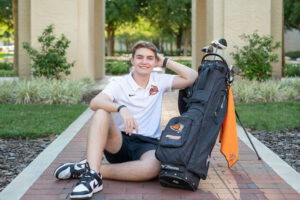 Winter Park senior photographer photographs teen boy with his golf clubs during a senior session.