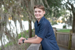 Senior boy standing by a lake in Winter Park