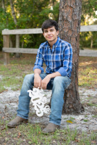 senior boy leaning on a tree for his senior photos in orlando