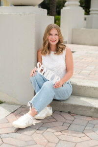 Orlando senior girl sits on a step for her senior photos with Oviedo senior photographer.