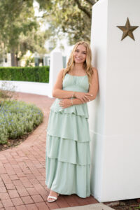 senior girl leaning on a white pillar in celebration, Fl