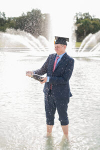 UCF graduate popping champagne at Reflecting Pond Orlando