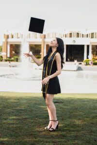 A UCF senior throws their graduation cap into the air while celebrating at the Reflecting Pond, captured by an Orlando graduation photographer.