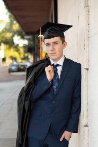 A senior boy in Winter park wears his cap and gown.