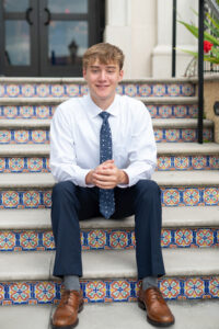 Senior boy in a suit sitting on stairs Orlando during his photo shoot
