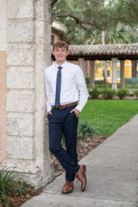 Orlando senior boy in a navy suit posing confidently outdoors during his photo session