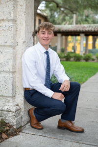 High school senior boy in a suit smiling at Rollins College during his Orlando photo session