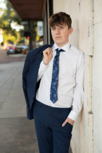 Senior boy in a blue suit leaning against a brick wall during his Orlando photo session